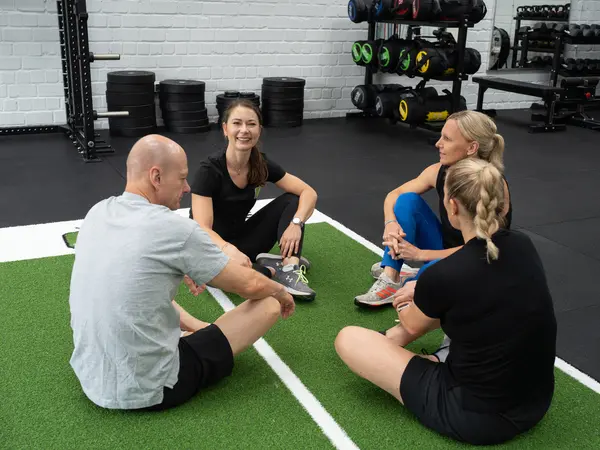 Iza Struck sitzt mit ihren Mitarbeitenden in der Trainingshalle des Big Apple Fitness Clubs